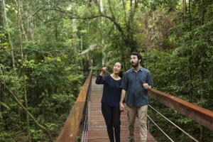 a man and woman walking on a bridge in the forest at Tambopata Research Center in Tambopata