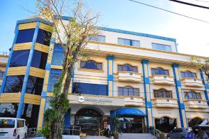 un edificio giallo e blu con macchine parcheggiate di fronte di Crown Royale Hotel a Balanga
