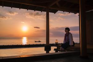 a woman sitting on a bench watching the sunset at Bousui in Higashiizu