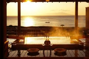 a room with a view of the ocean and a boat at Bousui in Higashiizu