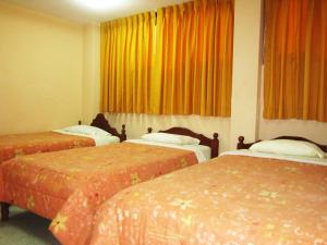 2 camas en una habitación de hotel con cortinas naranjas en Hostal Vista Hermosa, en Chachapoyas
