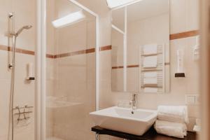 a white bathroom with a sink and a shower at Hotel . Wirtshaus TauernHex in Piesendorf