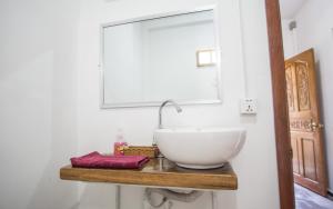 a bathroom with a white bowl sink on a wooden shelf at Om Home in Sihanoukville