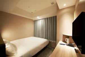 Habitación de hotel con cama y ventana en Sotetsu Fresa Inn Tokyo Kanda, en Tokio