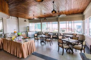 a dining room with tables and chairs and windows at Paradise Hotel in Phnom Penh