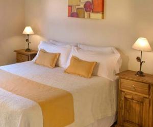 a bedroom with a large white bed with two lamps at El Portillo in Villa General Belgrano