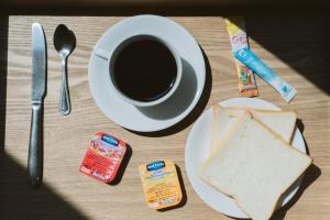 a table with a plate with a sandwich and a cup of coffee at Thomson Residence Hotel in Bangkok