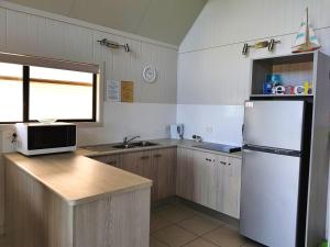 a kitchen with a refrigerator and a microwave at Cardwell Beachcomber Motel & Tourist Park in Cardwell