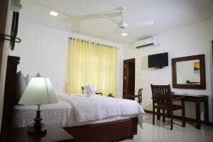 a bedroom with a bed and a desk and a chair at Hikka Sandy Pearl Beach Resort in Hikkaduwa