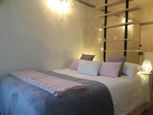 een slaapkamer met een bed met roze en witte kussens bij le studio Champlain in Honfleur