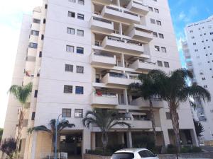 a white building with palm trees in front of it at Apartment 2 bedrooms Central Location in Ashdod
