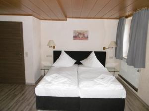 a bedroom with a large bed with white sheets at Gästepension zum Stern in Bühlertann