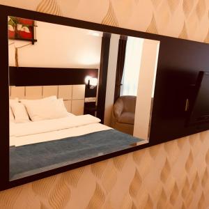 ein Spiegel, der ein Schlafzimmer mit einem Bett und einem Stuhl reflektiert in der Unterkunft Buyuk Velic Hotel in Gaziantep