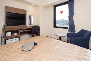 a hotel room with a bed and a flat screen tv at Sanco Inn Iseshi-Ekimae Shikinoyu in Ise