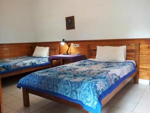 a bedroom with two beds and a lamp on a table at Madra Homestay in Ubud