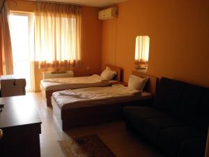 a hotel room with two beds and a couch at Hotel Pilevski in Blagoevgrad