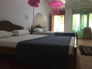 1 dormitorio con 2 camas y lámpara de color rosa en Margosa Guesthouse, en Mirissa