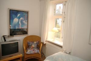 a bedroom with a tv and a chair and a window at Willes B&B in Copenhagen
