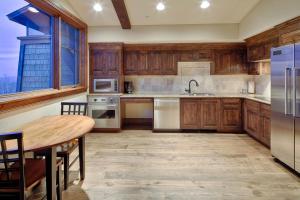 cocina con armarios de madera, mesa y nevera en Silver Strike #702 - 1 Bed, en Park City