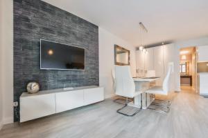 a living room with a desk and a television on a brick wall at Apartamenty Sun & Snow Zdrojowa in Świnoujście