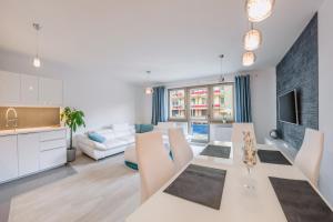 a kitchen and living room with a white table and chairs at Apartamenty Sun & Snow Zdrojowa in Świnoujście