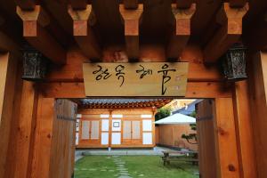 une entrée à un bâtiment avec un panneau sur celui-ci dans l'établissement Hanok Hyeyum, à Jeonju