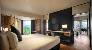 a bedroom with a bed and a desk with a television at PARKROYAL Penang Resort in Batu Ferringhi