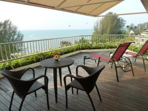 a table and chairs on a deck with the ocean at PARKROYAL Penang Resort in Batu Ferringhi