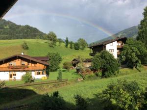 a rainbow over a house in a green field at Alpbach Apartments in Reith im Alpbachtal