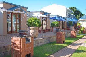 a row of houses with blue umbrellas in a yard at Oceans Hotel & Self Catering in Mossel Bay