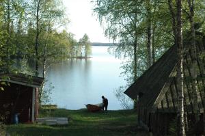 a man standing next to a boat on a lake at Ervastin Lomat in Heikkilä
