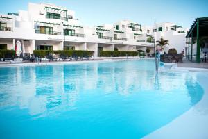 una gran piscina frente a un edificio en Apartamentos El Guarapo, en Costa Teguise