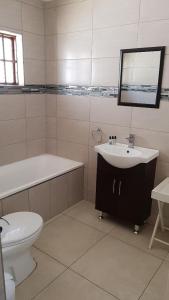 a bathroom with a sink and a tub and a toilet at The Grand Orchid Guesthouse in Durban