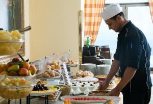 a chef preparing food in front of a buffet at Grand Hotel Due Golfi in SantʼAgata sui Due Golfi