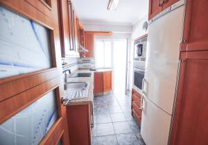 マラガにあるHolidays2Malaga Hermosilla 3 dormitorios & parking Wifi Fibra 600 MGのキッチン(木製キャビネット、白い冷蔵庫付)
