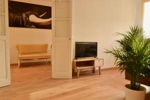Hola Valencia - Holiday Apartments في فالنسيا: غرفة معيشة فيها تلفزيون وكرسي