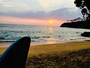 a person sitting on the beach watching the sunset at SunshineJP Guest House and bick rentel in Weligama