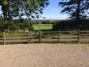 a wooden fence with a gate in a field at Scarlett Rose Cottage in Cookstown