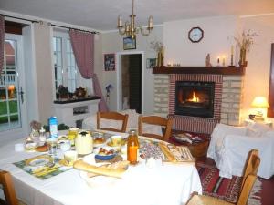 a dining room with a table and a fireplace at La Maison Claire in Longueville