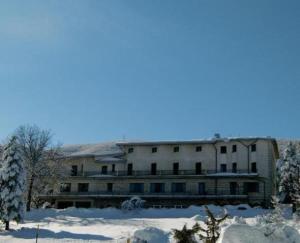 Un grand bâtiment blanc avec de la neige au sol dans l'établissement Hotel El Senor, à Pretoro