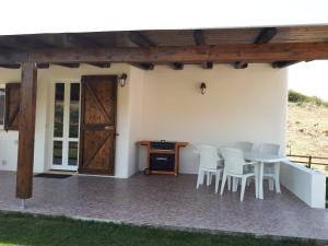 eine Terrasse mit Tisch und Stühlen und einer Holztür in der Unterkunft Su Pasciale in Nulvi