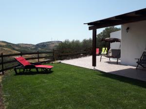 eine Terrasse mit einer roten Bank auf dem Rasen in der Unterkunft Su Pasciale in Nulvi