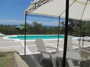 un par de sillas y una sombrilla junto a la piscina en Cabañas El Mirador en Embalse