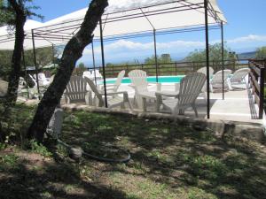 un grupo de sillas blancas y una piscina en Cabañas El Mirador en Embalse