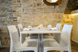 a table with white chairs and a stone wall at Suite Luna Bianca in Assisi