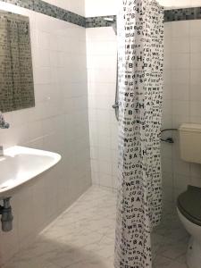 La salle de bains est pourvue d'un rideau de douche et d'un lavabo. dans l'établissement Villa Elfi, aux Sables d'or