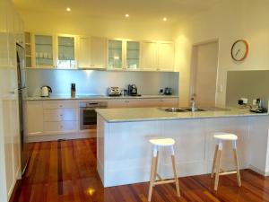 een keuken met witte kasten en een aanrecht met krukken bij The Holiday House in Fraser Island
