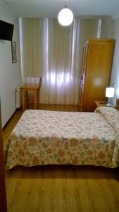 a bedroom with a bed and a table and a chair at Hostal El Cairo in Ferrol