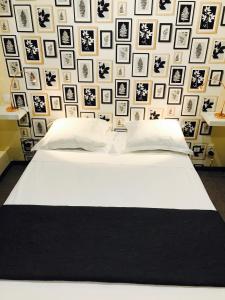 Un dormitorio con una cama blanca y una pared de cuadros. en Hôtel Beauséjour, en Marsella