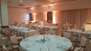uma grande sala com mesas brancas e cadeiras em Hotel Pula em Pula
